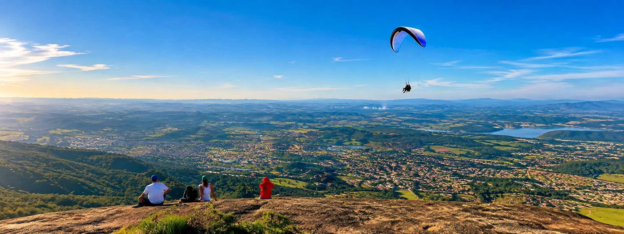 Vista panorâmica de Atibaia do alto da serra, com parapente no céu azul